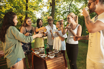 Image showing Happy friends eating and drinking beers at barbecue dinner on sunset time