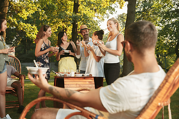 Image showing Happy friends eating and drinking beers at barbecue dinner on sunset time