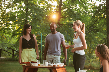 Image showing Happy friends eating and drinking beers at barbecue dinner on sunset time