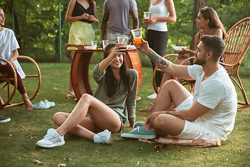 Image showing Happy friends eating and drinking beers at barbecue dinner on sunset time