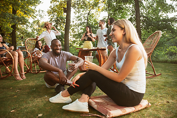 Image showing Happy friends eating and drinking beers at barbecue dinner on sunset time