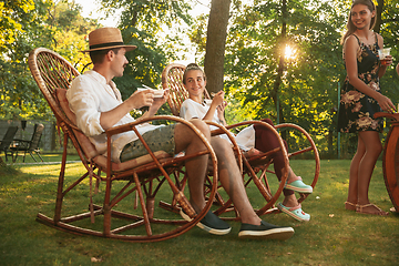 Image showing Happy friends eating and drinking beers at barbecue dinner on sunset time