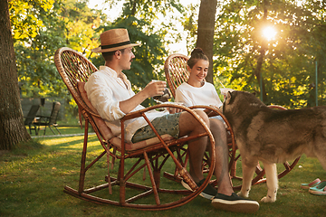 Image showing Happy couple eating and drinking beers at barbecue dinner on sunset time