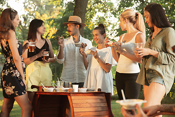 Image showing Happy friends eating and drinking beers at barbecue dinner on sunset time