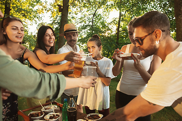 Image showing Happy friends eating and drinking beers at barbecue dinner on sunset time