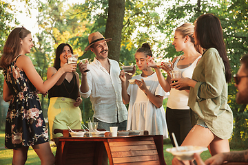 Image showing Happy friends eating and drinking beers at barbecue dinner on sunset time