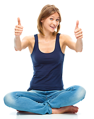 Image showing Young happy woman is showing thumb up sign