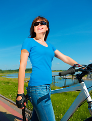 Image showing Young woman is standing in front of her bicycle