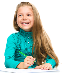 Image showing Little girl is drawing using pencils