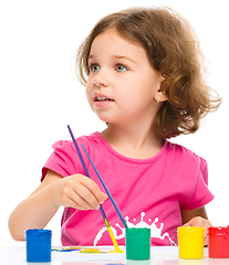 Image showing Little girl is painting with gouache