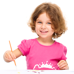 Image showing Little girl is painting with gouache