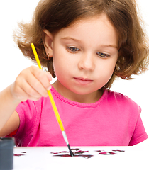 Image showing Little girl is painting with gouache