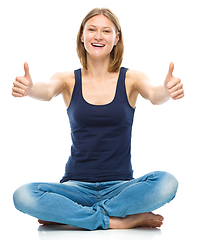 Image showing Young happy woman is showing thumb up sign