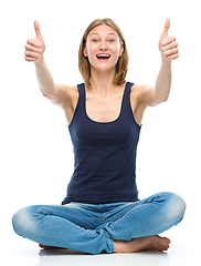 Image showing Young happy woman is showing thumb up sign