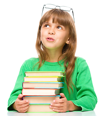 Image showing Young girl is daydreaming while reading book