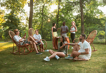 Image showing Happy friends eating and drinking beers at barbecue dinner on sunset time