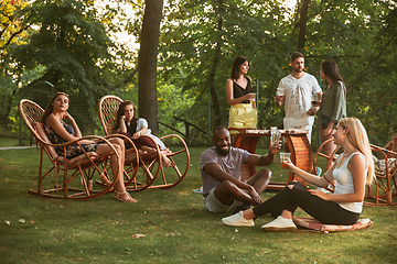 Image showing Happy friends eating and drinking beers at barbecue dinner on sunset time