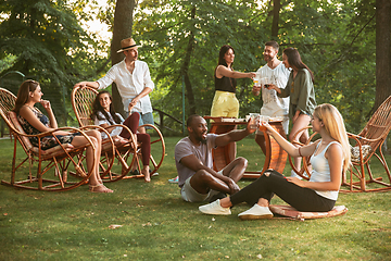 Image showing Happy friends eating and drinking beers at barbecue dinner on sunset time