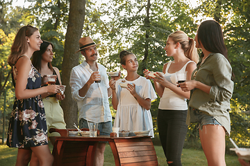 Image showing Happy friends eating and drinking beers at barbecue dinner on sunset time