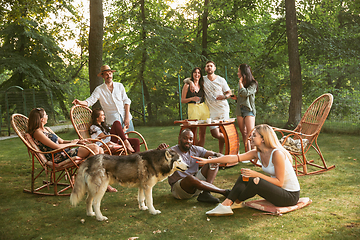 Image showing Happy friends eating and drinking beers at barbecue dinner on sunset time