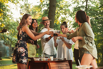 Image showing Happy friends eating and drinking beers at barbecue dinner on sunset time