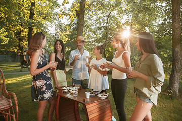 Image showing Happy friends eating and drinking beers at barbecue dinner on sunset time