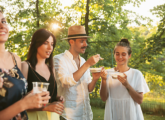 Image showing Happy friends eating and drinking beers at barbecue dinner on sunset time