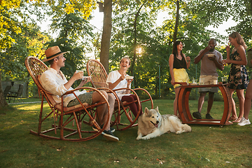 Image showing Happy friends eating and drinking beers at barbecue dinner on sunset time