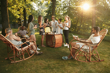 Image showing Happy friends eating and drinking beers at barbecue dinner on sunset time