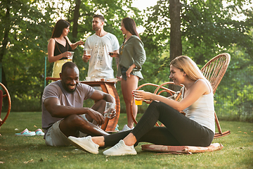 Image showing Happy friends eating and drinking beers at barbecue dinner on sunset time