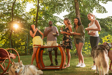 Image showing Happy friends eating and drinking beers at barbecue dinner on sunset time