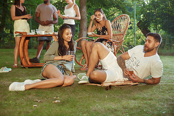 Image showing Happy friends eating and drinking beers at barbecue dinner on sunset time