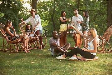 Image showing Happy friends eating and drinking beers at barbecue dinner on sunset time