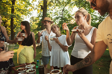 Image showing Happy friends eating and drinking beers at barbecue dinner on sunset time