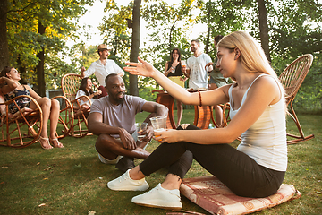 Image showing Happy friends eating and drinking beers at barbecue dinner on sunset time