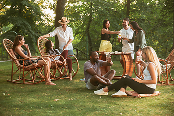 Image showing Happy friends eating and drinking beers at barbecue dinner on sunset time