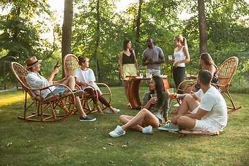 Image showing Happy friends eating and drinking beers at barbecue dinner on sunset time