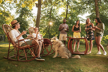 Image showing Happy friends eating and drinking beers at barbecue dinner on sunset time