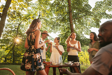 Image showing Happy friends eating and drinking beers at barbecue dinner on sunset time