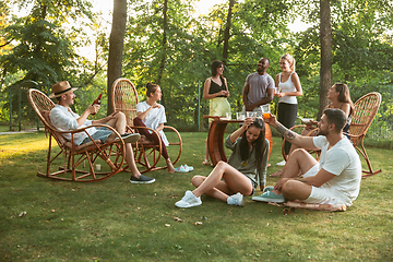 Image showing Happy friends eating and drinking beers at barbecue dinner on sunset time