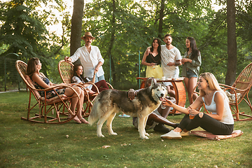 Image showing Happy friends eating and drinking beers at barbecue dinner on sunset time