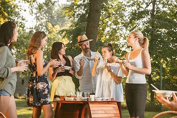 Image showing Happy friends eating and drinking beers at barbecue dinner on sunset time