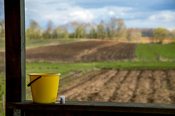 Image showing Yellow bucket next to the plowed field.