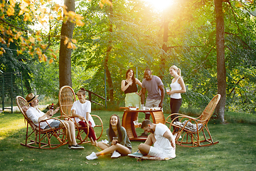 Image showing Happy friends eating and drinking beers at barbecue dinner on sunset time