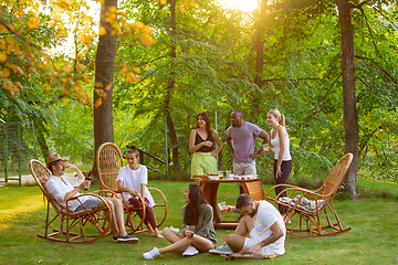 Image showing Happy friends eating and drinking beers at barbecue dinner on sunset time