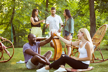 Image showing Happy friends eating and drinking beers at barbecue dinner on sunset time