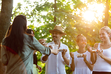 Image showing Happy friends eating and drinking beers at barbecue dinner on sunset time