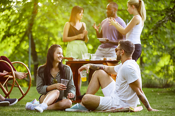 Image showing Happy friends eating and drinking beers at barbecue dinner on sunset time