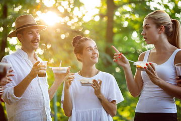 Image showing Happy friends eating at barbecue dinner on sunset time