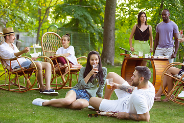 Image showing Happy friends eating and drinking beers at barbecue dinner on sunset time